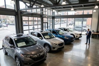 Vue large d'un showroom automobile moderne présentant plusieurs SUV neufs alignés avec étiquettes de prix visibles
