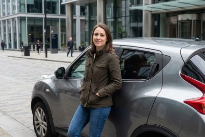 Jeune femme urbaine en veste près d'une voiture moderne